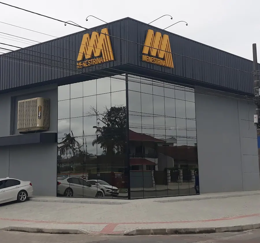 Prédio da Menestrina com fachada grafite, vidro e o M amarelo